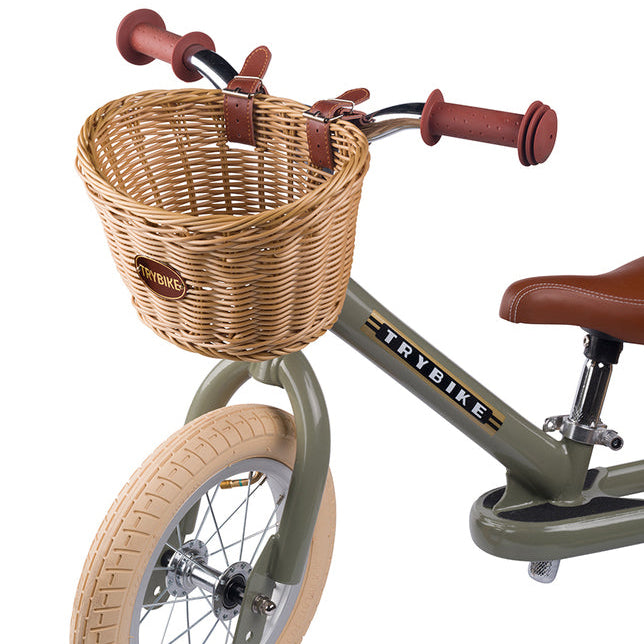 Children's balance bike with wicker basket and brown handlebar grips on a white background