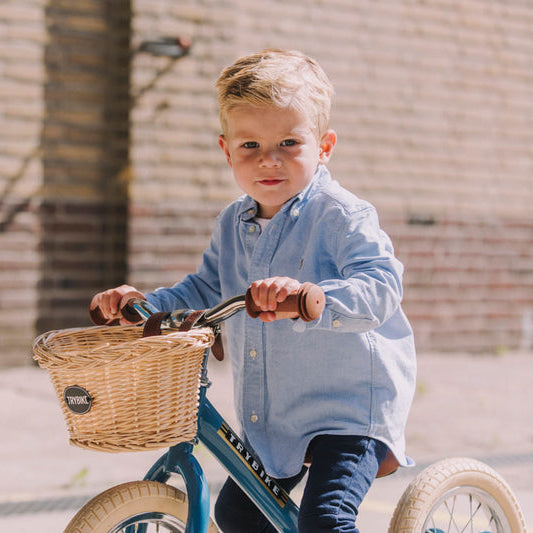 Child riding a balance bike with a basket in an outdoor setting