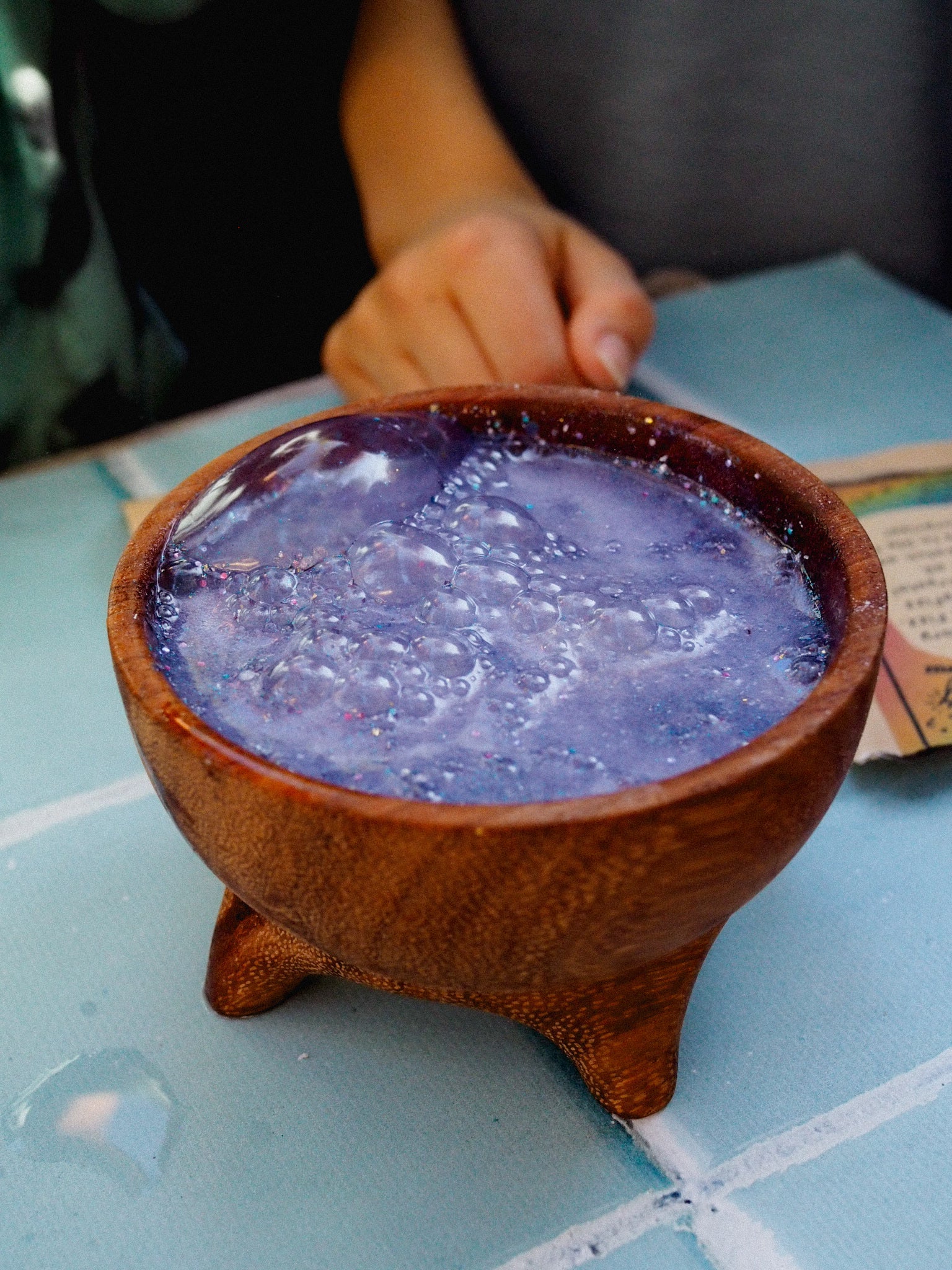 Purple liquid in a wooden bowl on a light blue tiled surface