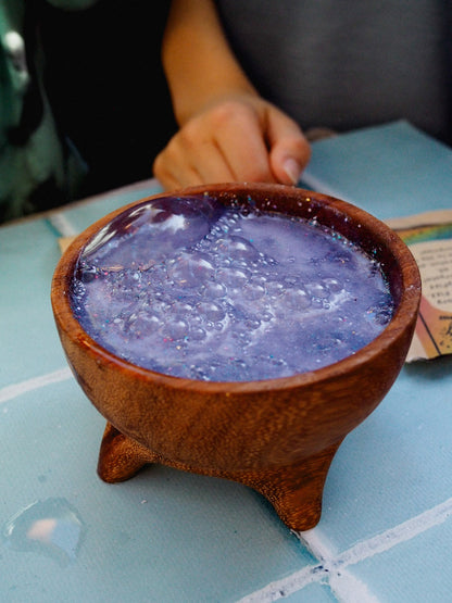 Purple liquid in a wooden bowl on a light blue tiled surface