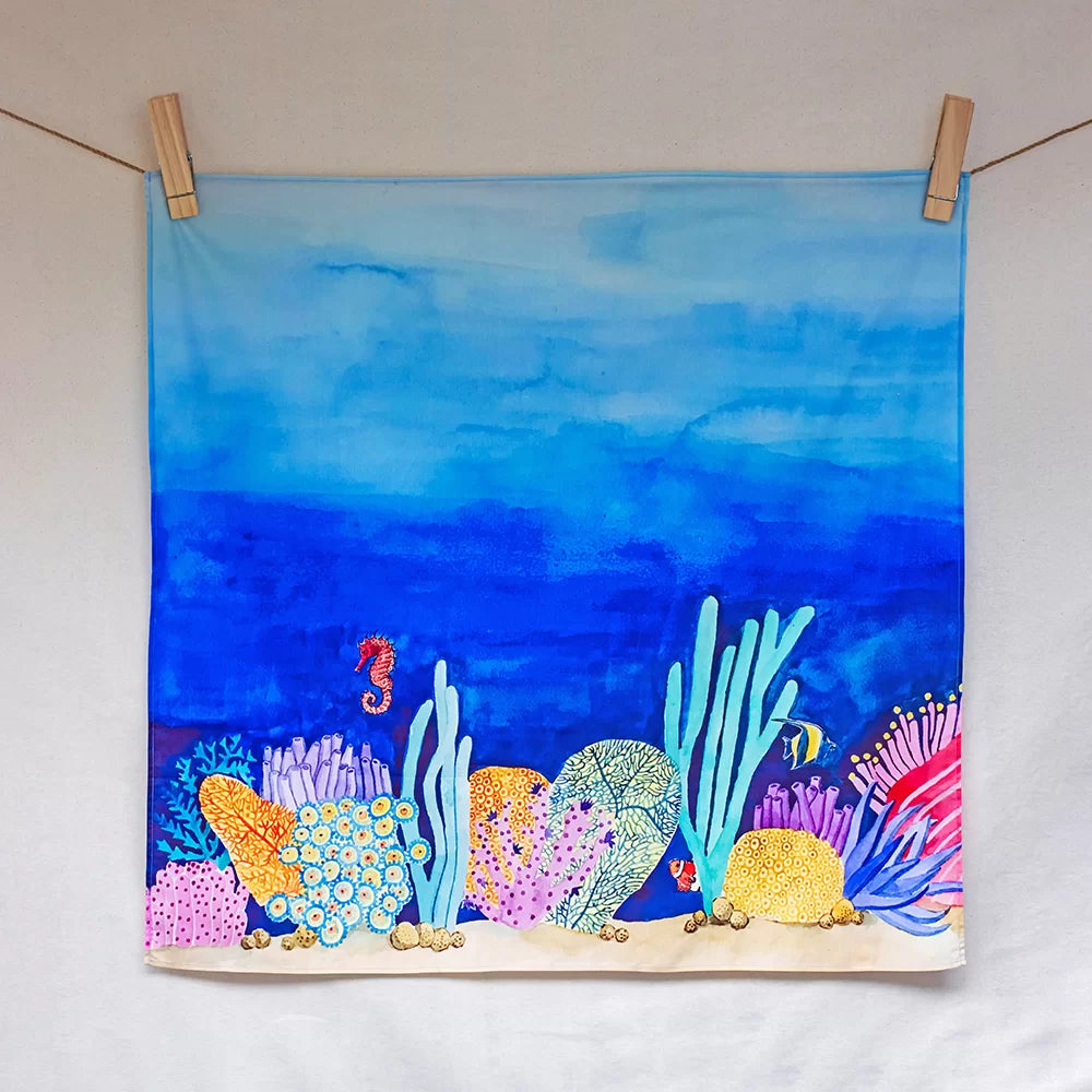 Colorful underwater scene with sea creatures and coral on a towel hanging on a line.