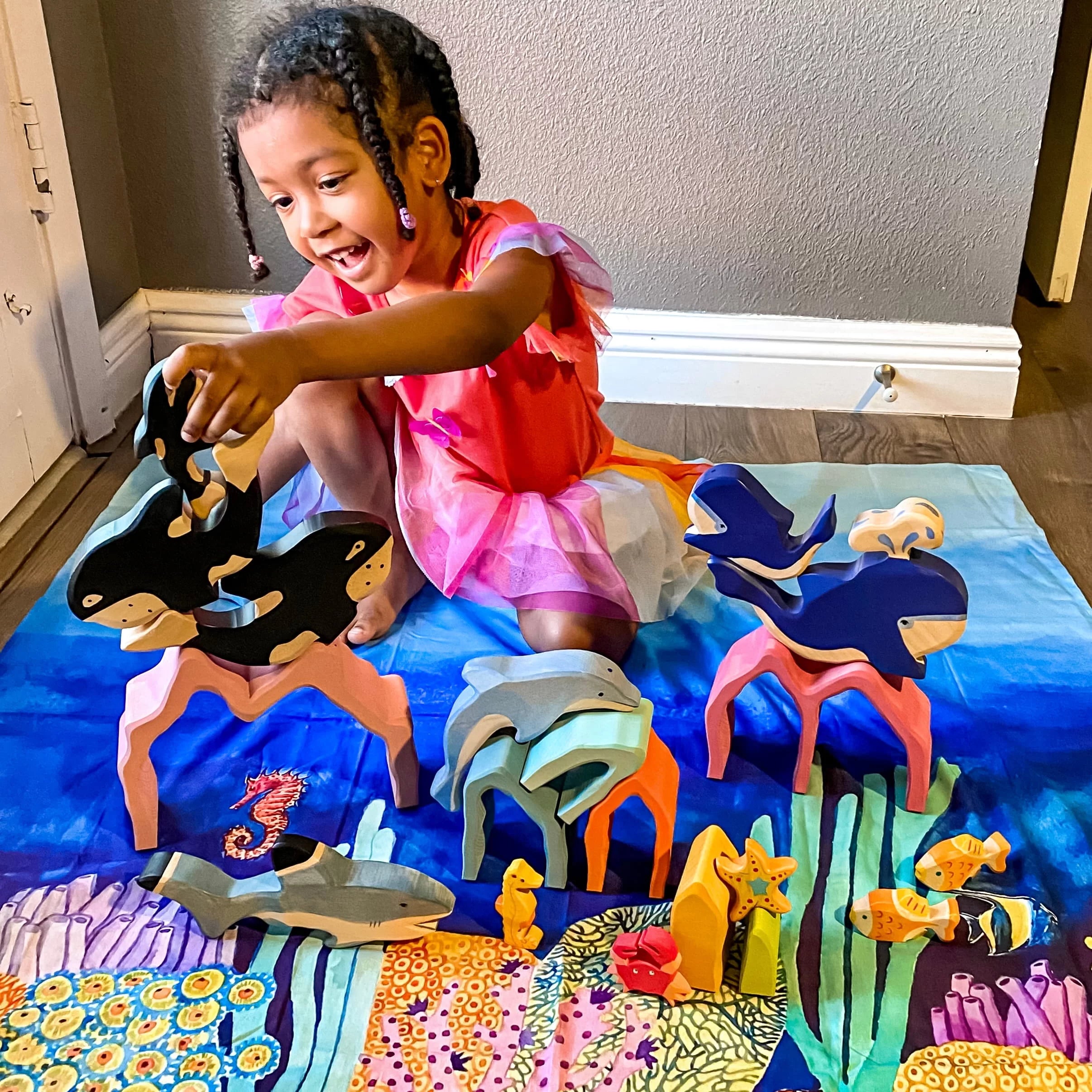 Child playing with toy whales on a colorful mat