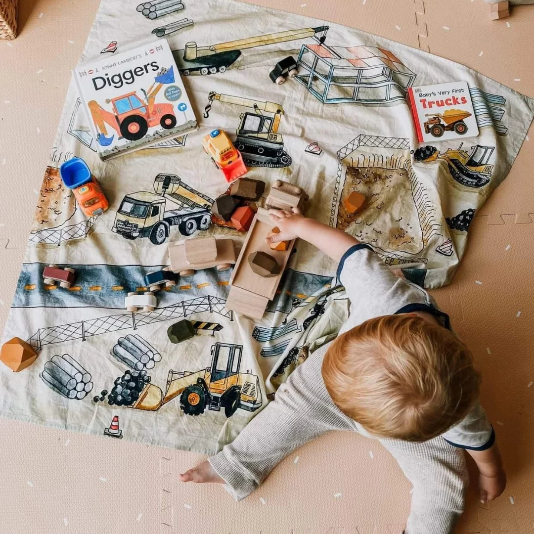 Child playing with toy trucks on a construction-themed play mat