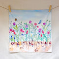 Colorful floral painting hanging on a line with wooden clips.
