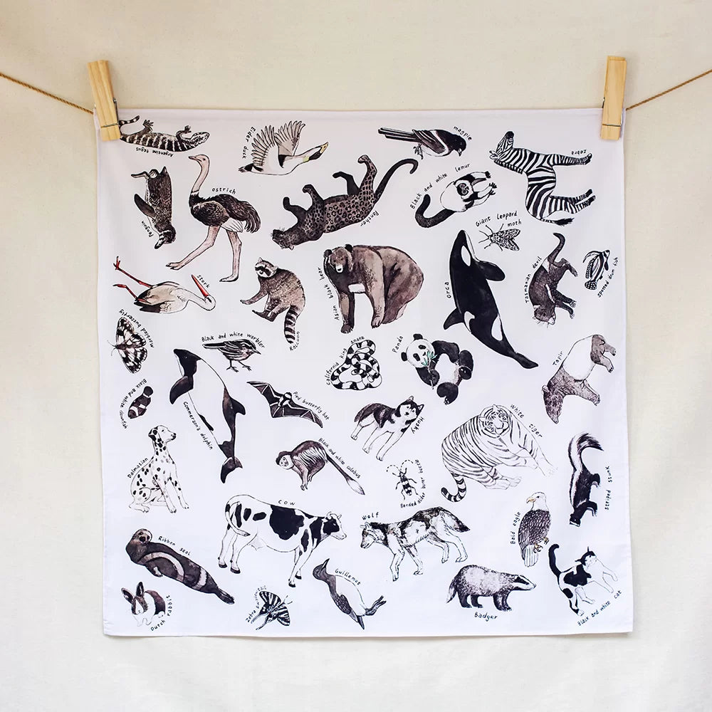 White towel with black animal illustrations hanging on a line.
