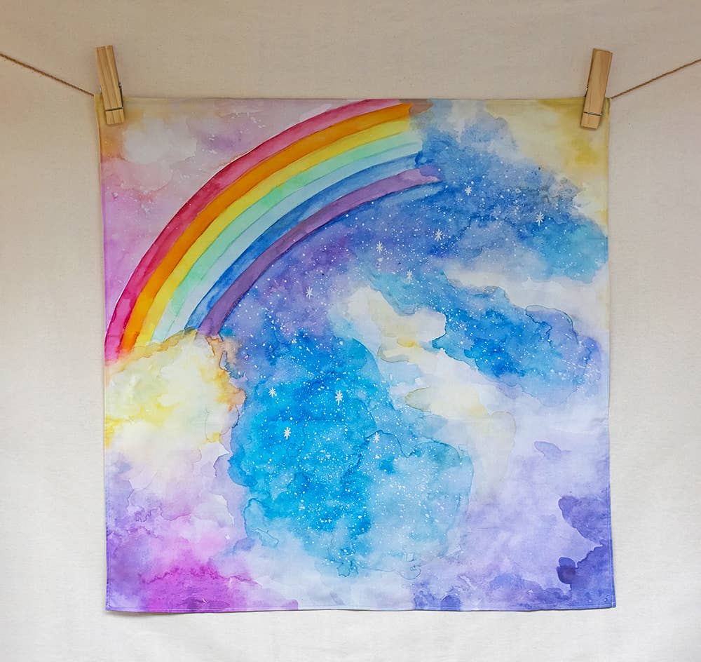 Colorful rainbow painting on a white wall with wooden clips.