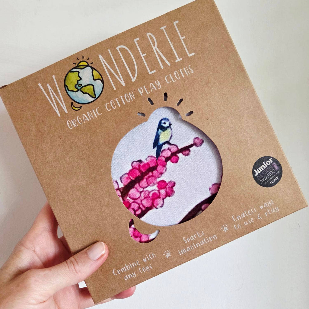 Wonderie organic cotton play cloth packaging held by a hand on a white background