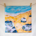 Colorful beach scene with rocks, sand, and sea creatures hanging on a line.