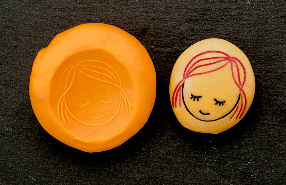 Orange and yellow cookie cutters with engraved faces on a black background