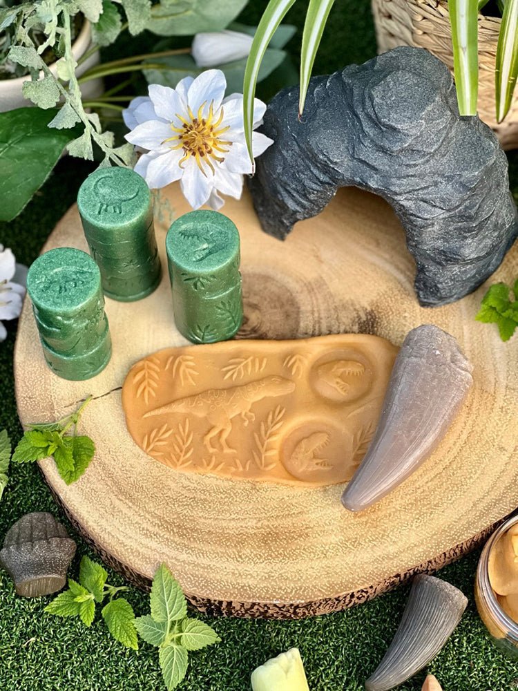 Decorative display with green rollers and play dough, and decorative stones on a wooden surface.