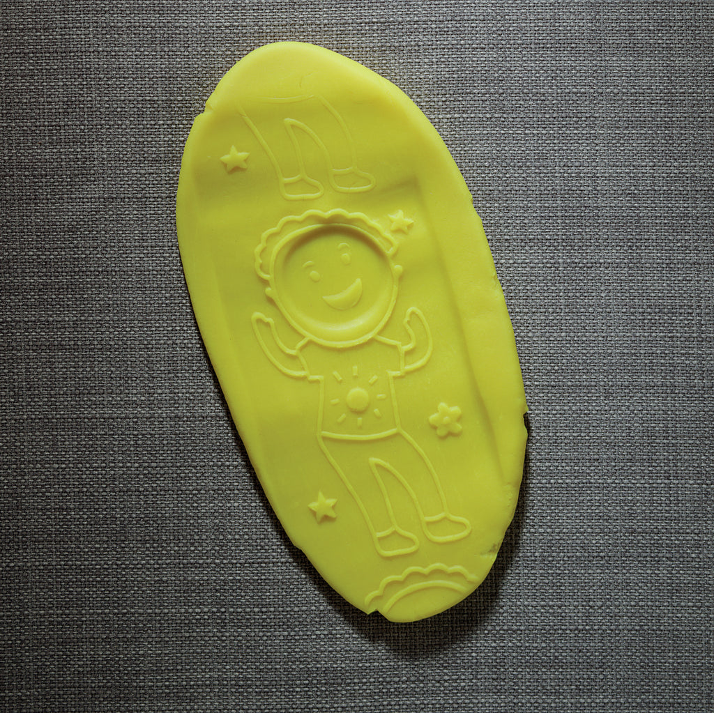Yellow toy with astronaut design on a gray textured background