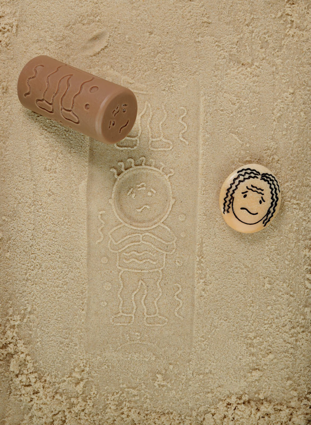 Sand mold with a child's face and body impression on sand