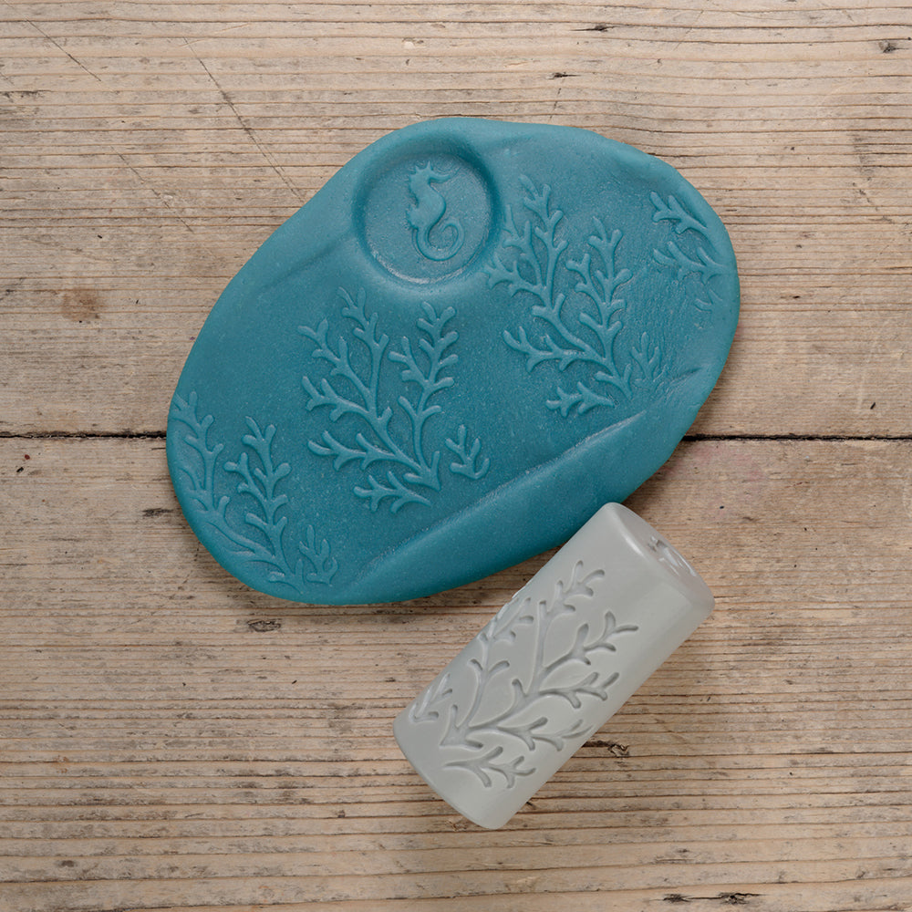 Teal silicone mold with floral patterns on a wooden surface
