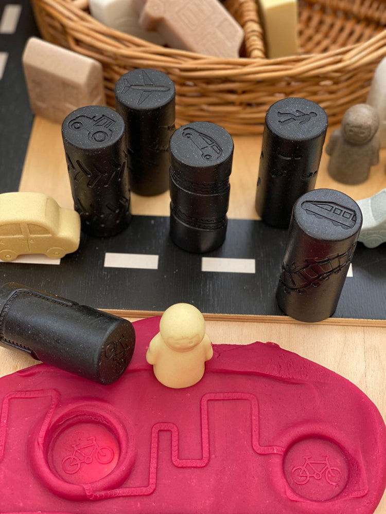 Toy construction set with black cylindrical blocks and a pink truck-shaped mold on a wooden surface.